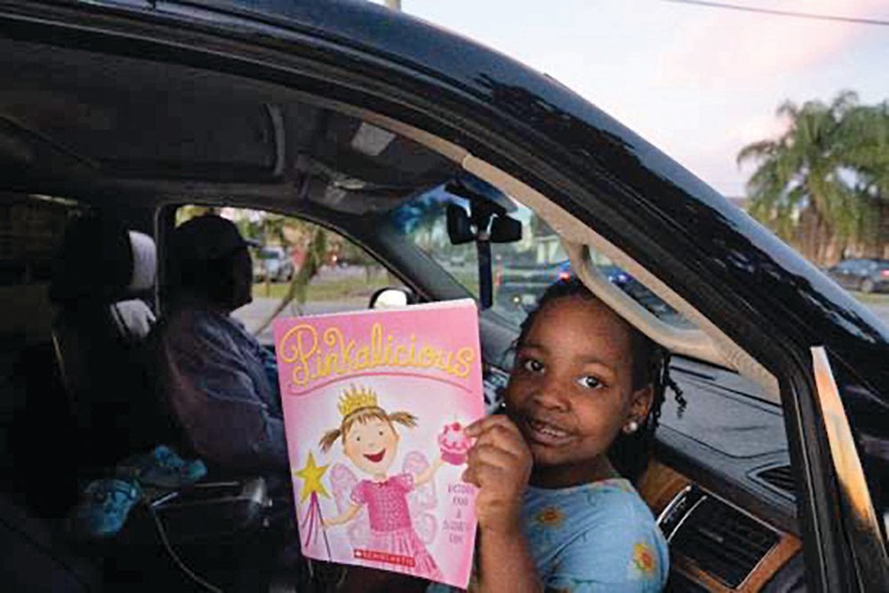 A Belle Glade youth enjoys her Pinkalicious book.